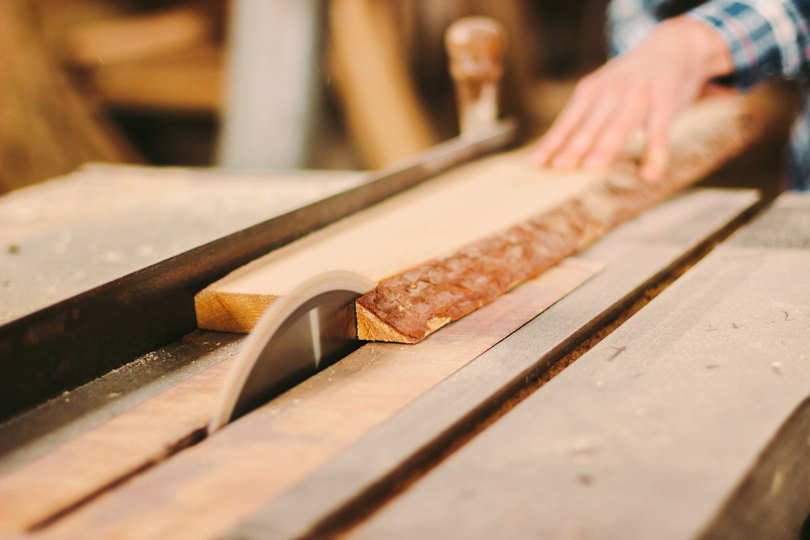 Jemand verwendet eine Säge, um Holz auf einem Tisch zu schneiden.
